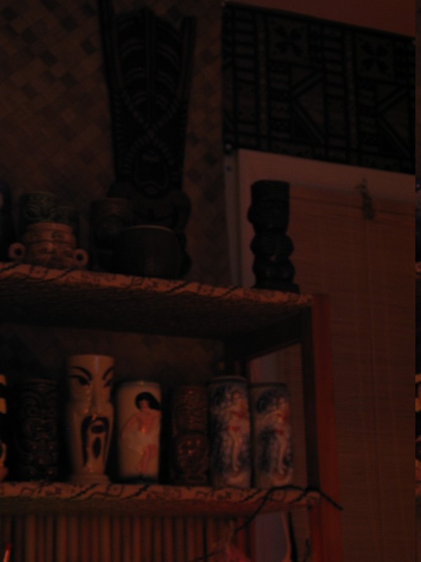 On the wall is one of the two TikiZone carvings that guard the sides of the bar. At the front of the mugshelves on top is one of two 'doorhandles' from Oceanic Arts- they watch over the Lounge from their perches.