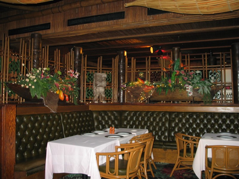 One of several larger back dining rooms. Here, the rattan chairs are still in place. Note the canoes laden with lush foliage, the Tikis, the tiles, and how every surface is part of the experience.