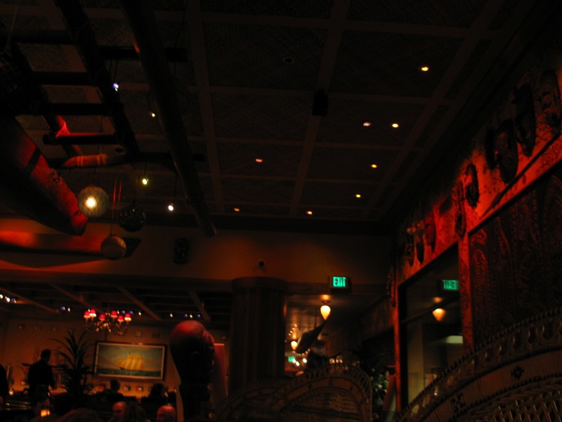 In the bar area, looking towards a dining room and the entrance hall. A wall of tapa and masks along the right wall.